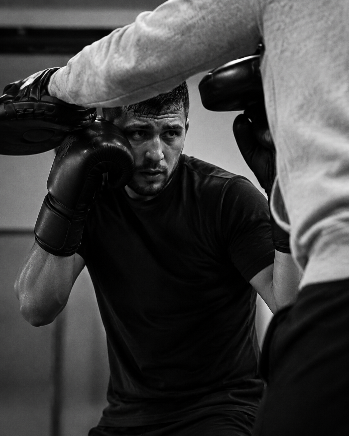 Imagen de referencia generada: boxeador en guardia y torso y brazos de su entrenador, sin mostrar la cara del entrenador ni marcas